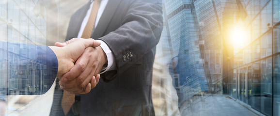 Business partnership meeting concept. Businessmen making handshake in the city. Successful businessmen handshaking after good deal withe Double exposure city background