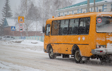 yellow bus for children, winter movement in a blizzard