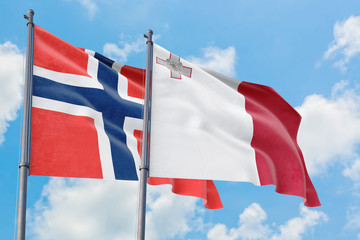 Malta and Bouvet Islands flags waving in the wind against white cloudy blue sky together. Diplomacy concept, international relations.