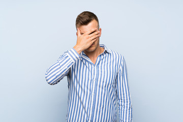 Young handsome blonde man over isolated blue background covering eyes by hands. Do not want to see something