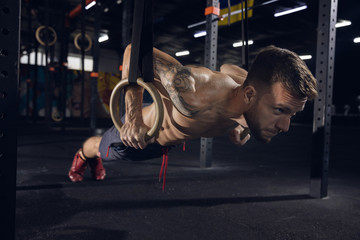 Fototapeta na wymiar Young healthy man, athlete doing exercises, pull-ups in gym. Single caucasian model practicing hard, training his upper body. Concept of healthy lifestyle, sport, fitness, bodybuilding, wellbeing.