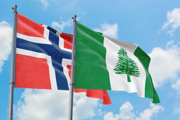 Norfolk Island and Bouvet Islands flags waving in the wind against white cloudy blue sky together. Diplomacy concept, international relations.