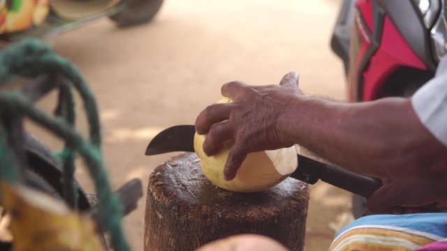 Dark-skinned man chops the coconut with machete clse-up (4K, 25fps)