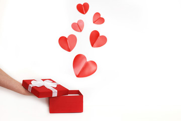 hands of a young man holding a present box with red hearts on a white background