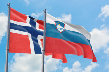 Slovenia and Bouvet Islands flags waving in the wind against white cloudy blue sky together. Diplomacy concept, international relations.