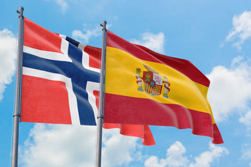 Spain and Bouvet Islands flags waving in the wind against white cloudy blue sky together. Diplomacy concept, international relations.