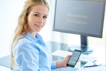 Businesswoman using her cell phone while working in the office