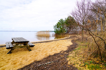 wood table and wooden bench in sand beach in french lake of Sanguinet France