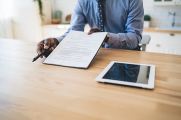 Black man in formal clothes giving contract and pen