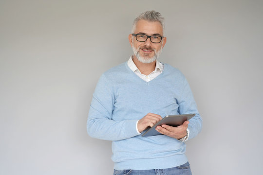Middle-aged man using tablet, isolated on grey background