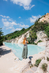 Fototapeta premium Young female traveler enjoying by the natural turquoise pools in Bagno Vignoni spa in Tuscany, Italy