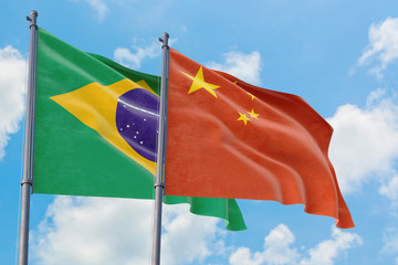 China and Brazil flags waving in the wind against white cloudy blue sky together. Diplomacy concept, international relations.