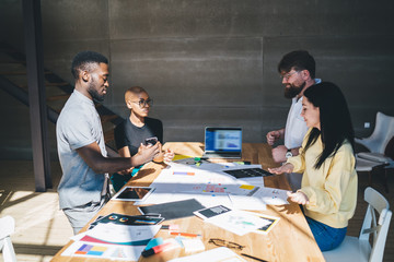 Group of multiracial people standing and looking at design on table