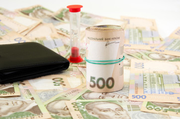 twisted 500 hryvnias against the background of hryvnias, wallet and hourglass. Business concept. Ukrainian money.