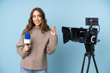 Reporter young woman holding a microphone and reporting news with fingers crossing