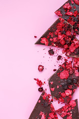 Broken chocolate bar pieces with scattered dried red berries and crumbs