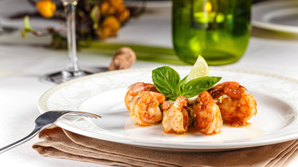 Spanish, Italian cuisine. King prawns with sauce. Serving dishes in a restaurant on a white plate, next to a glass of white wine. background image, copy space text