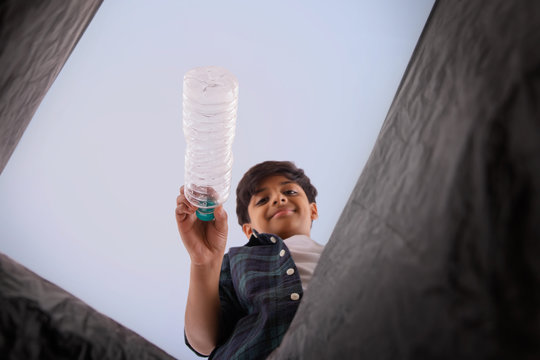 Young boy throwing waste in a garbage bag. (Children)