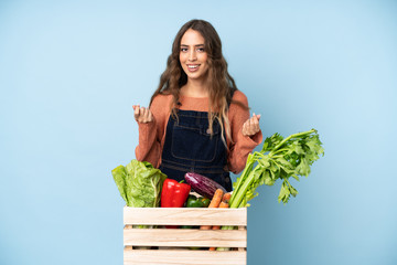 Farmer with freshly picked vegetables in a box making money gesture