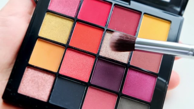 Close up a palette with colorful eye shadows and a makeup brush. Decorative women's cosmetics. Make-up artist. Evening and morning make-up.
