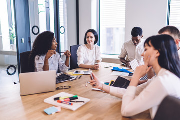 Young multiracial inventive colleagues using gadgets at business meeting at office