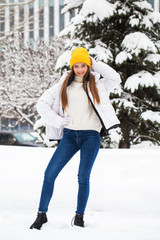 Full-length portrait of a young cheerful woman in a white down jacket