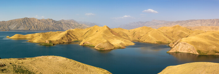 Panorama of the Nurek reservoir and its blue water with golden shores