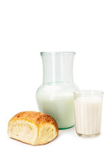 Milk in a glass decanter with a glass, muffin on a white background
