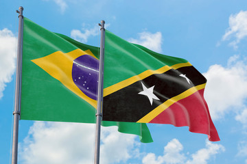 Saint Kitts And Nevis and Brazil flags waving in the wind against white cloudy blue sky together. Diplomacy concept, international relations.
