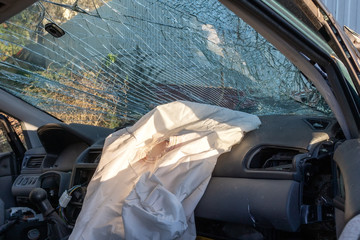 Blown up airbag after a car crash and broken glass. Problems drinking alcohol while driving.