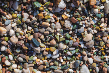 Closeup top view of colourful cute smooth rounded stones at beach of sea shore. Abstract organic natural photo background.