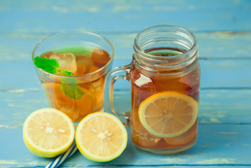 Iced tea with lemon slices and mint on wood background