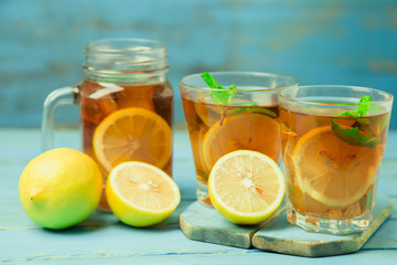 Iced tea with lemon slices and mint on wood background
