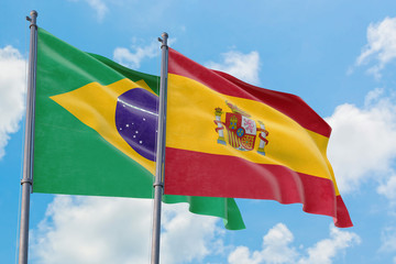Spain and Brazil flags waving in the wind against white cloudy blue sky together. Diplomacy concept, international relations.