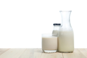 Milk in glass and in jar on table isolated on white background