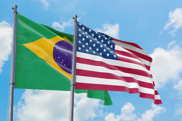 United States and Brazil flags waving in the wind against white cloudy blue sky together. Diplomacy concept, international relations.