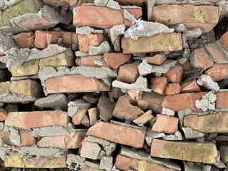 Old destroyed red brick wall on the ground. The wreckage of a dumped brick house. Background texture: pieces of stone wall.