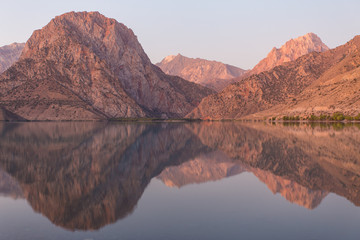 Mirror surface of Lake Iskanderkul at dawn amid the mountains