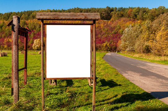 Blank white advertisement/annoucement board on the meadow. Sunny autumn day