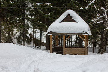 Wooden picnic gazebo in the snow-covered Carpathian Mountains. Road to the highest mountain of...