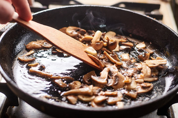 Fried mushrooms in a pan. Cooking mushrooms with steam emanating from them.