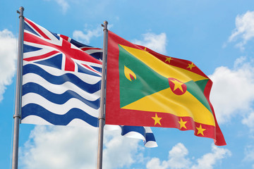 Grenada and British Indian Ocean Territory flags waving in the wind against white cloudy blue sky together. Diplomacy concept, international relations.