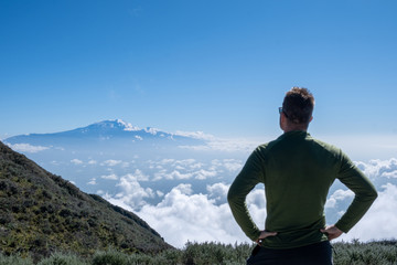 young man with a green shirt looking at Kilimanjaro in Tanzania Africa