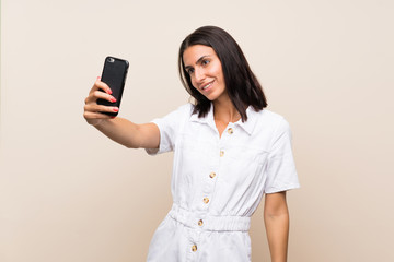 Naklejka premium Young woman over isolated background making a selfie