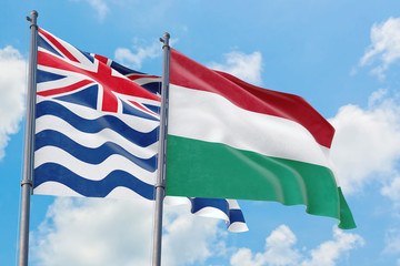 Hungary and British Indian Ocean Territory flags waving in the wind against white cloudy blue sky together. Diplomacy concept, international relations.