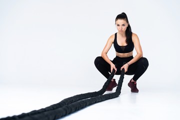 Fototapeta na wymiar Woman doing exercises with battle rope. Photo of muscular model in sportswear isolated on white background