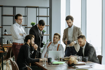 brainstorming time of business team in office, young men gathered together in office for discussing and sharing ideas, planning strategy in modern boardroom, everyone in formal wear