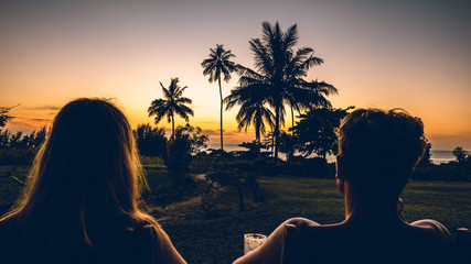 a young couple watching the sunset with palm trees in Tanzania Africa