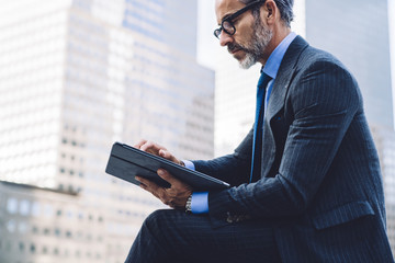 Middle-aged man working in tablet in city