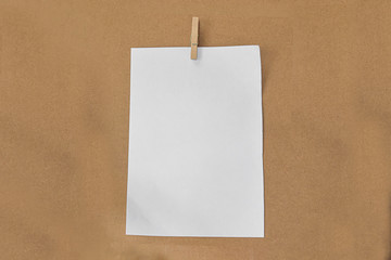 White paper and wood clip on brown paper background.